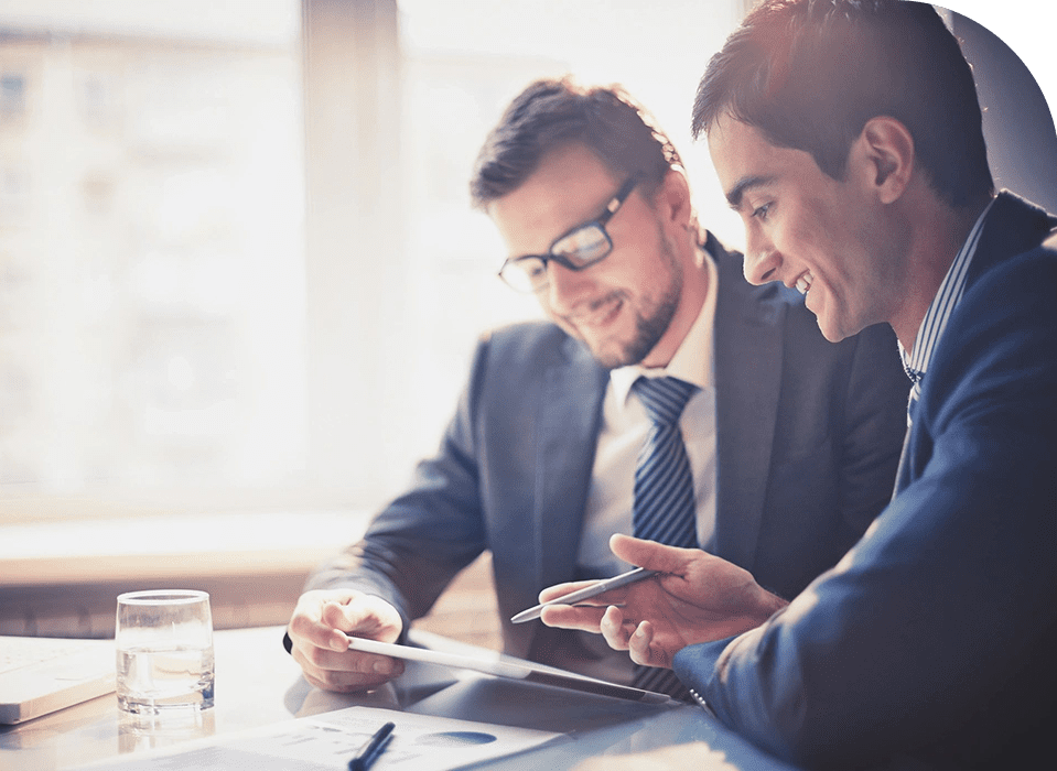 Two men in suits looking at a tablet.