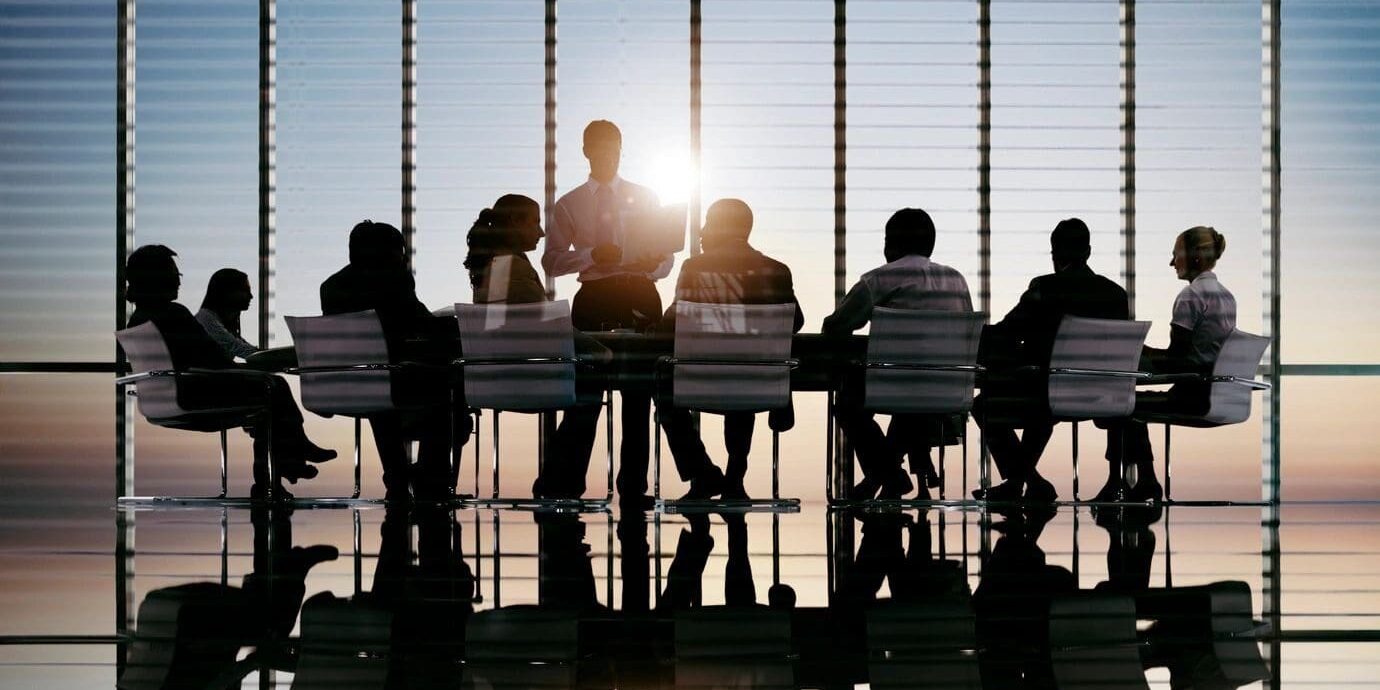 A group of people sitting at a table in front of a window.